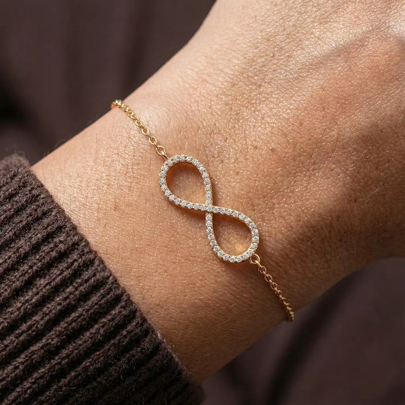 Gold-plated infinity bracelet with pavé CZ stones, worn on the wrist.