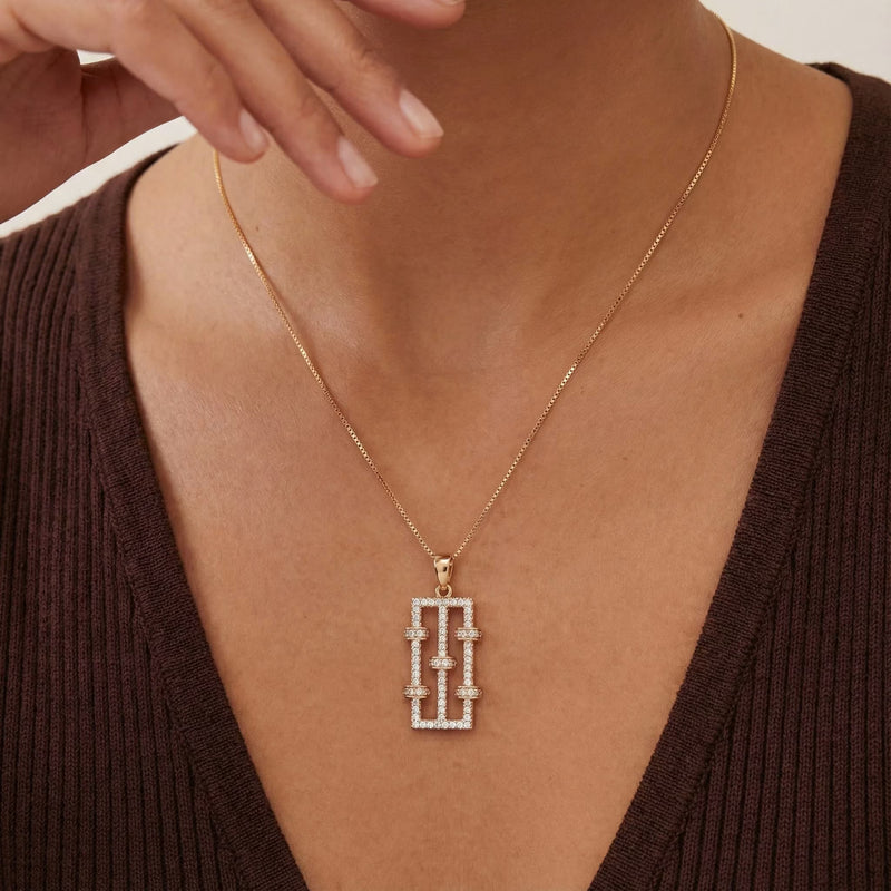 Gold-plated pendant necklace with a rectangular pavé link motif worn at the collarbone.