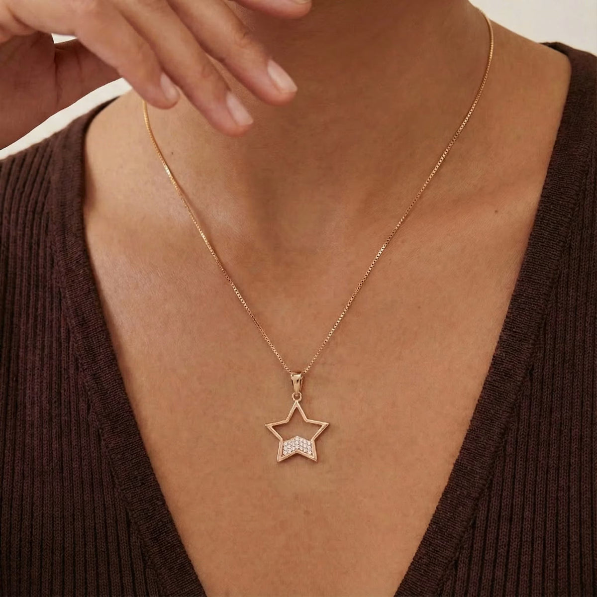 Gold-plated star outline pendant necklace with pavé CZ accent detail, worn at the collarbone.