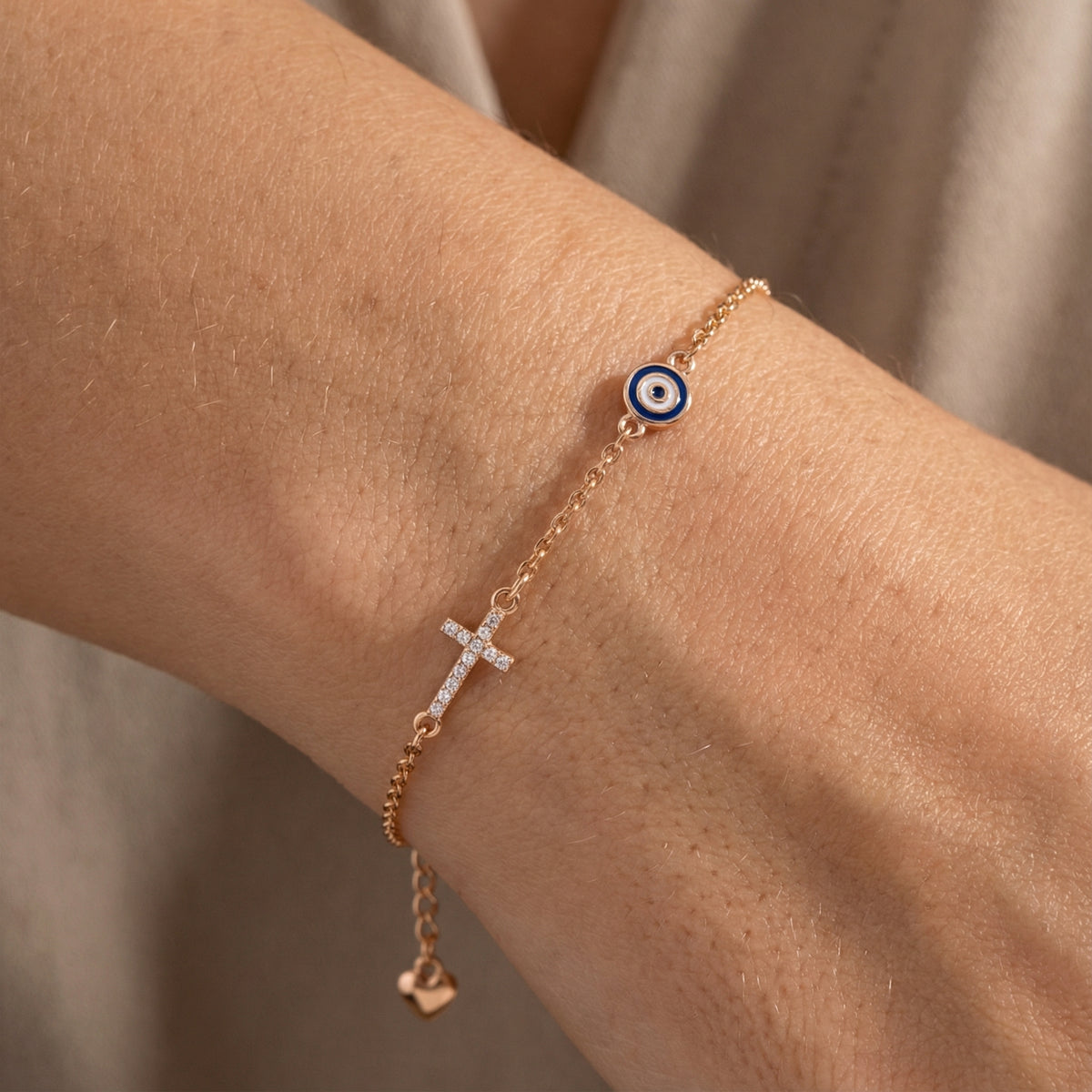 Clear stone cross and evil eye charm bracelet worn on the wrist