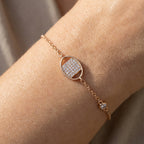 Gold-plated bracelet featuring pavé square charm within smooth oval frame worn on wrist