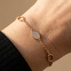 Gold-plated oval charm bracelet worn on wrist