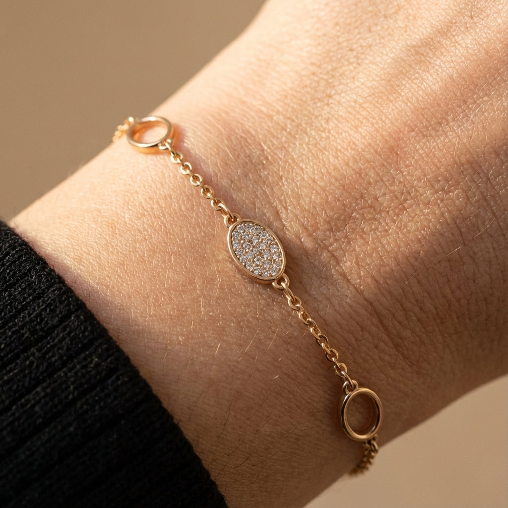 Gold-plated oval charm bracelet worn on wrist