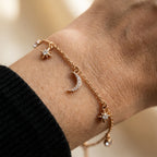 Gold-plated moon and star charm bracelet worn on wrist