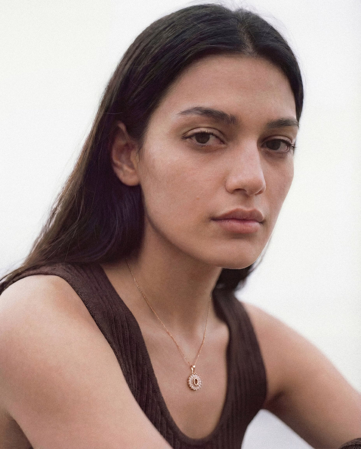 Model wearing a gold-plated round halo pendant necklace with clear stones.